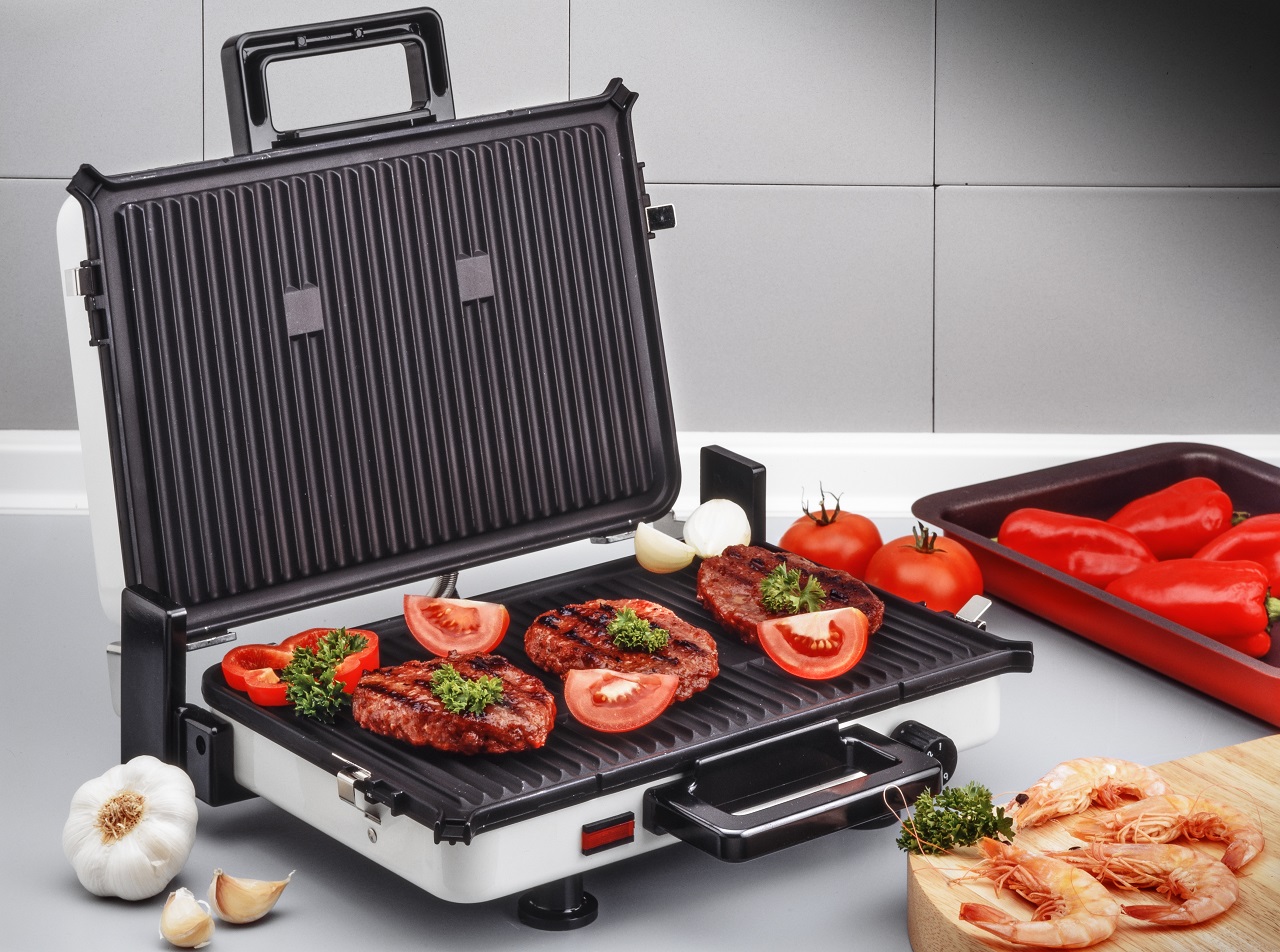 electric-grill-with-burgers-and-prawns-on-kitchen-board
